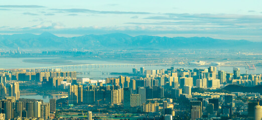 Modern Xiamen city in China sprawls with tall buildings, a long bridge crossing the bay, and...