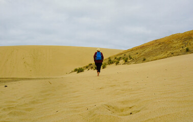 A woman walking on the Giant Sand Dunes, Cape Reinga, New Zealand.