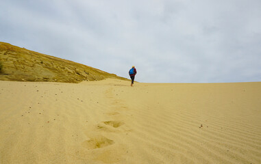 A woman walking on the Giant Sand Dunes, Cape Reinga, New Zealand.