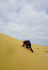 A woman walking on the Giant Sand Dunes, Cape Reinga, New Zealand.