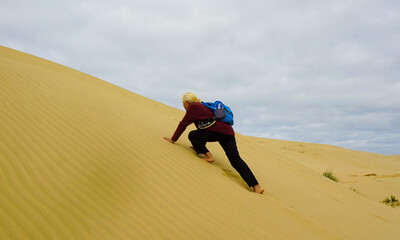 A woman walking on the Giant Sand Dunes, Cape Reinga, New Zealand.