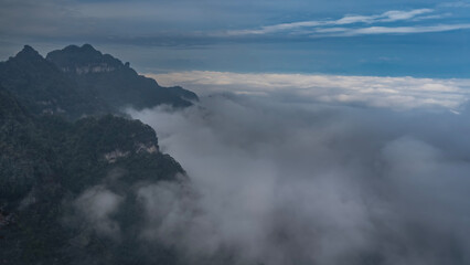 Beautiful misty mountain landscape. Peaks above the clouds. Green vegetation on the slopes. The blue sky. China. Zhangjiajie. Tianmen Mountain