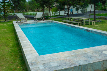Empty swimming pool with sunbed and white umbrella in resort hotel for vacation leisure and white sand,resort neary sea and beach in summer.