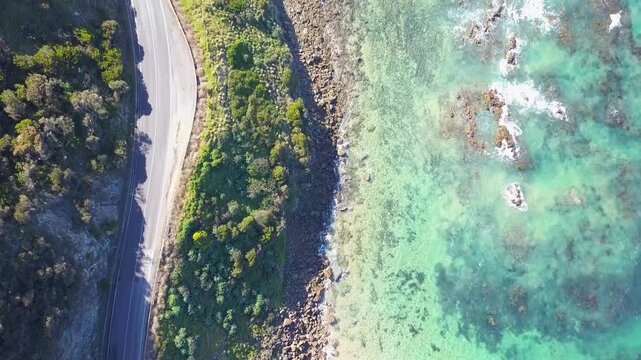 Scenic aerial of the Great Ocean Road, Victoria, Australia, featuring steep cliffs, turquoise waters, and lush greenery along the winding shoreline - DLOG Flat File 4K