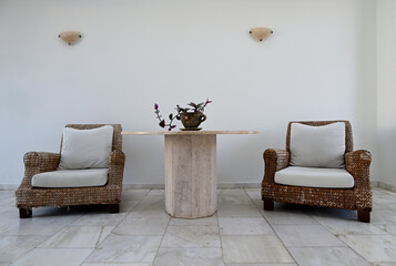 Ein Raum mit zwei gemütlichen Sesseln und einem Tisch, der von einer Zimmerpflanze geschmückt wird