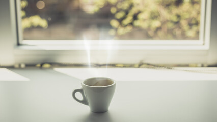 Espresso hot cup of coffee put on table near the window