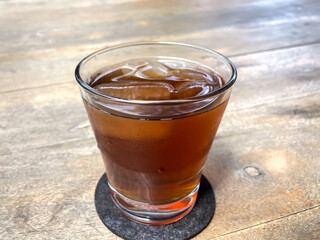 A Refreshing Glass of Iced Tea with Ice Cubes on a Rustic Wooden Table.