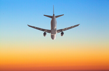 Passenger airplane flying at sunset with orange and blue sky