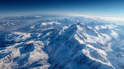 Stunning aerial view of vast, snow-capped mountain ranges bathed in crisp daylight