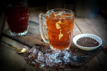 Refreshing iced black tea with lemon on wooden background. Vintage style