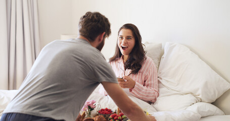 Surprise, love and couple with breakfast in bed for anniversary, romance or weekend break together. Happy, shocked and man with morning meal for wife in bedroom for marriage celebration in home.