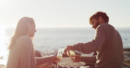 Beach, picnic and couple with love, alcohol and bonding together with vacation, date or romance. Ocean, champagne or man with woman, anniversary or celebration with holiday, honeymoon or relationship