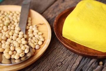Soybeans and yellow tofu on wood background
