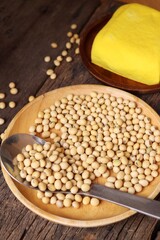 Soybeans and yellow tofu on wood background