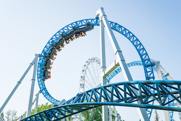 Roller coaster Ride against blue sky. Roller coaster in the amusement park. Cheerful entertainments...