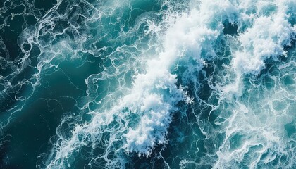 Fototapeta premium Overhead view of a powerful wave cresting, foam and spray scattering across the surface of deep teal colored ocean water