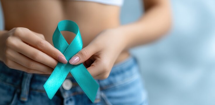 Close up of woman holding teal awareness ribbon for supporting Cervical Cancer, Ovarian Cancer, Polycystic Ovary Syndrome, Sexual Assault Awareness and other health problems - Powered by Adobe