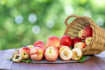 Fresh peach drop from bamboo basket on blurred greenery background, Peach fruit in Bamboo basket on wooden table in garden.