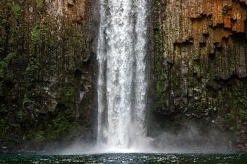 Waterfall cascading down a mossy cliff into a clear pool.