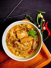 Braised duck noodle soup served in a bowl with fresh herbs and green onions. Tender duck with rich, flavorful broth and soft noodles, a traditional Thai comfort food.