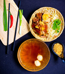 Thai braised pork leg noodle soup served in a bowl with fresh herbs, boiled egg, and green onions. Tender pork leg and rich savory broth with soft noodles, a traditional and appetizing Thai comfort fo