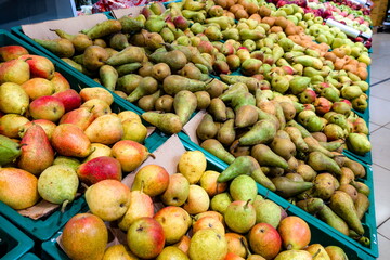 Variety of fresh pears in a market during the morning, showcasing different colors and textures in a vibrant environment
