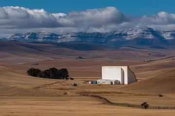 Rural White Building in Brown Field with Distant Mountains. Mock up promotion information for marketing announcements and details, blank white space.