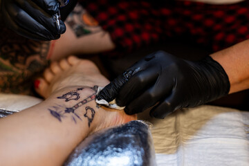 Tattoo artist carefully working on a client’s leg design under focused light. Concept of precision, artistry, creativity, and modern body art in a professional tattoo studio