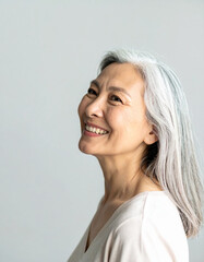 Fototapeta premium a half-body portrait of an elderly Asian woman captures her warm, radiant smile and neatly styled silver hair.