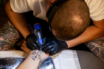 Tattoo artist carefully working on a client’s leg design under focused light. Concept of precision, artistry, creativity, and modern body art in a professional tattoo studio