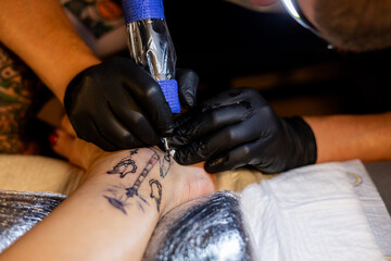 Tattoo artist carefully working on a client’s leg design under focused light. Concept of precision, artistry, creativity, and modern body art in a professional tattoo studio