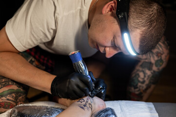 Tattoo artist carefully working on a client’s leg design under focused light. Concept of precision, artistry, creativity, and modern body art in a professional tattoo studio