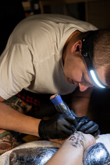 Tattoo artist carefully working on a client’s leg design under focused light. Concept of precision, artistry, creativity, and modern body art in a professional tattoo studio