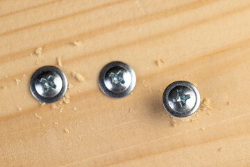self-tapping screws with a drill tip twisted into a board, close up