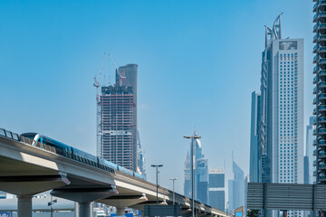 Metro on bridge with highrise buildings in background, Dubai metro in downtown 