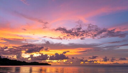 A vibrant sunset paints the sky in hues of orange, pink, and purple over a calm shoreline, showcasing a dramatic and peaceful atmosphere.