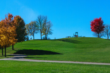 Scenic Park Landscape with Autumn Colored Trees and Playground on Sunny Day