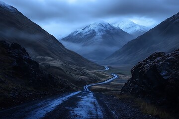 Dramatic mountain valley under moody twilight skies with snow capped peaks and winding river