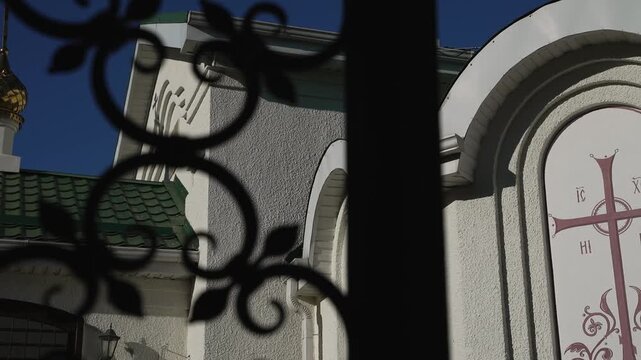 View of an Orthodox church with white walls through black fence