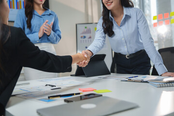 Businesswomen shaking hands after successful meeting in modern office