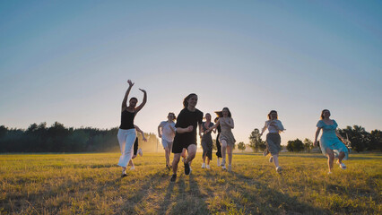 High school students are happily frolicking in a field at sunset, embracing the carefree joy of their summer vacation