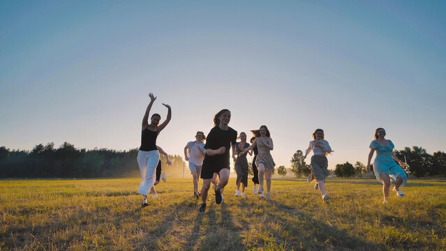 High school students are happily frolicking in a field at sunset, embracing the carefree joy of their summer vacation