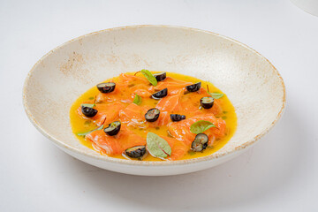 Salmon fillets nestled in a zesty sauce, garnished with fresh herbs and olives, tempt the palate