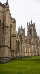 Fototapeta premium Detailed exterior view of a historic Gothic-style cathedral featuring tall towers, arched stained-glass windows, and ornate stonework