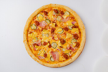 A mouthwatering pizza featuring toppings of ham, pickles, cheese, and savory sausage awaits diners