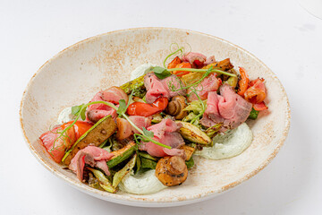 A vibrant arrangement of roasted vegetables and tender beef garnished with fresh herbs