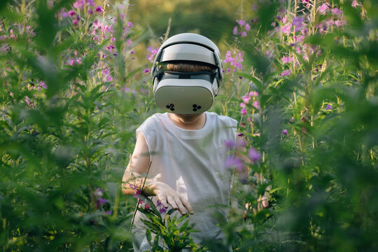 Man child in virtual reality glasses walks in tall grass