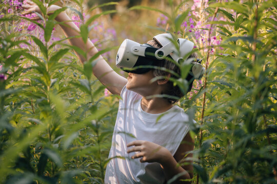 Man child in virtual reality glasses playing in tall grass