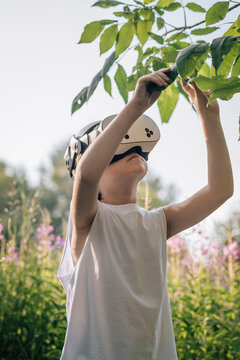 Man child in virtual reality glasses touches leaves