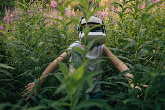 Man child in virtual reality glasses in tall grass